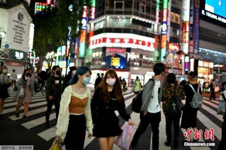 　当地时间5月25日，东京新宿区，戴口罩的人们穿过街道。