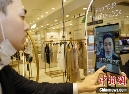 图为在韩国首尔爱茉莉太平洋清凉里店，工作人员正在展示一款AR试妆镜，可自助进行皮肤诊断，“亲身”试涂不同颜色口红、眼影等。 曾鼐 摄