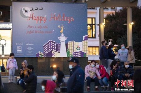 　　当地时间11月21日，美国加州旧金山市民在联合广场上一块写着“假期快乐”的广告牌前休息。 中新社记者 刘关关 摄