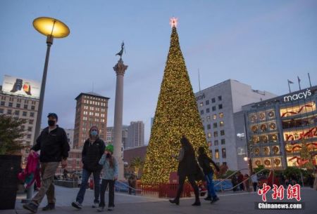 　　当地时间11月21日，美国旧金山市民从联合广场的圣诞树前经过。这棵高度超过25米的圣诞树装饰有超过33000盏节能LED灯和1100件装饰品。受新冠肺炎疫情影响，今年的圣诞树亮灯仪式日前以简单的方式举行。 中新社记者 刘关关 摄