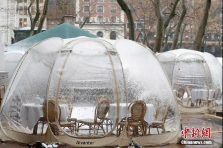 资料图：当地时间12月9日，美国纽约迎来今冬首场降雪，布莱恩公园的户外用餐“泡泡屋”覆盖白雪。中新社记者 廖攀 摄