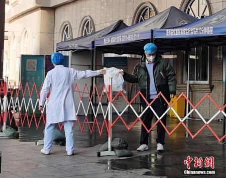 　1月5日，河北医科大学附属第二医院急诊楼封闭，工作人员隔着栅栏交接物品。 中新社记者 翟羽佳 摄