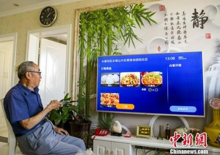 　　资料图：新疆乌鲁木齐市团结社区，老人通过电视订第二天的中餐。 中新社记者 刘新 摄