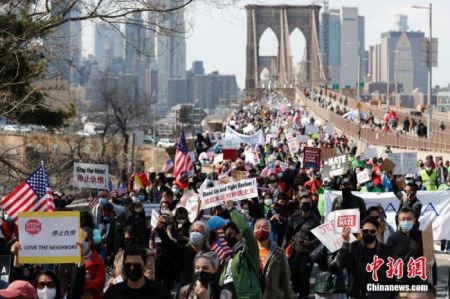 　　当地时间4月4日，纽约举行反仇恨亚裔大游行，上万民众手持标语在曼哈顿弗利广场集会后，游行穿过布鲁克林大桥至布鲁克林卡德曼广场。图为民众游行穿过布鲁克林大桥。 中新社记者 廖攀 摄